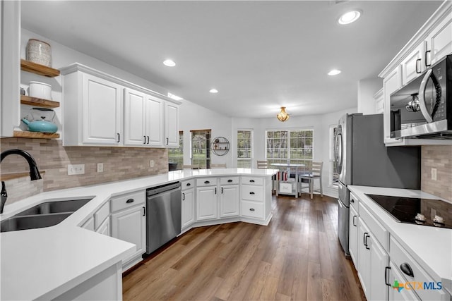 kitchen featuring open shelves, a sink, a peninsula, appliances with stainless steel finishes, and white cabinetry