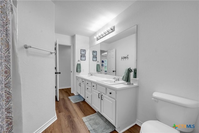 bathroom with wood finished floors, toilet, and a sink