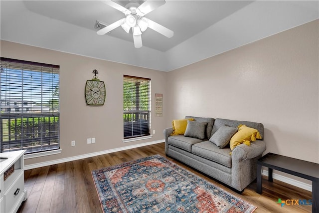 living area with ceiling fan, baseboards, visible vents, and dark wood-style floors