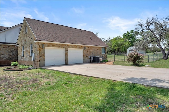 view of side of home featuring concrete driveway, a lawn, a shingled roof, fence, and a garage