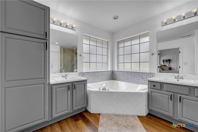 full bath with wood finished floors, visible vents, a stall shower, and a sink