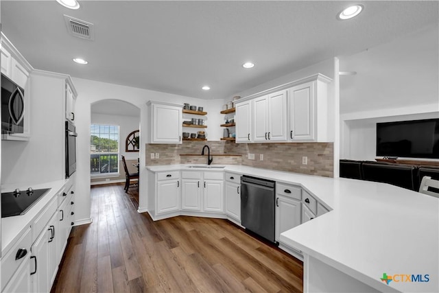 kitchen with white cabinets, arched walkways, a sink, visible vents, and black appliances