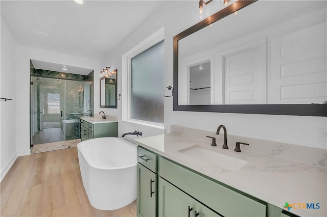 4146 Turning Leaf Dr, Nolanville, TX 76559 - bathroom with a freestanding bath, a stall shower, wood finished floors, two vanities, and a sink