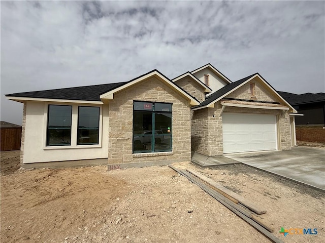 ranch-style home with fence, roof with shingles, a garage, stone siding, and driveway