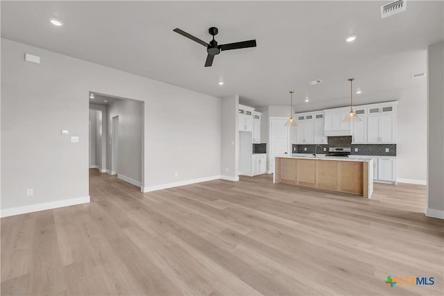 kitchen featuring white cabinetry, backsplash, hanging light fixtures, a large island, and ceiling fan