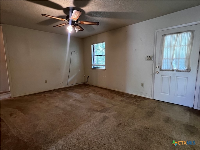 carpeted entrance foyer featuring a textured ceiling and ceiling fan