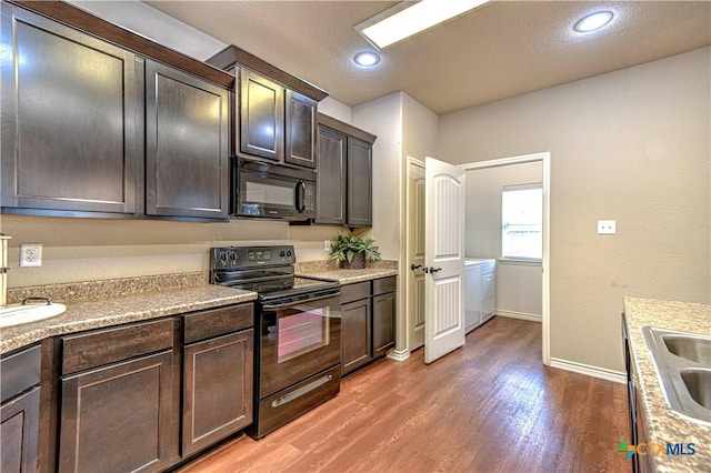 kitchen featuring dark brown cabinetry, light wood-style flooring, black appliances, and light countertops