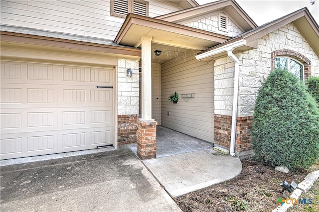 property entrance featuring stone siding, brick siding, and driveway