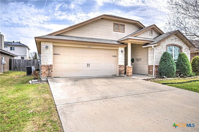 craftsman-style home featuring central air condition unit, driveway, fence, a front yard, and a garage