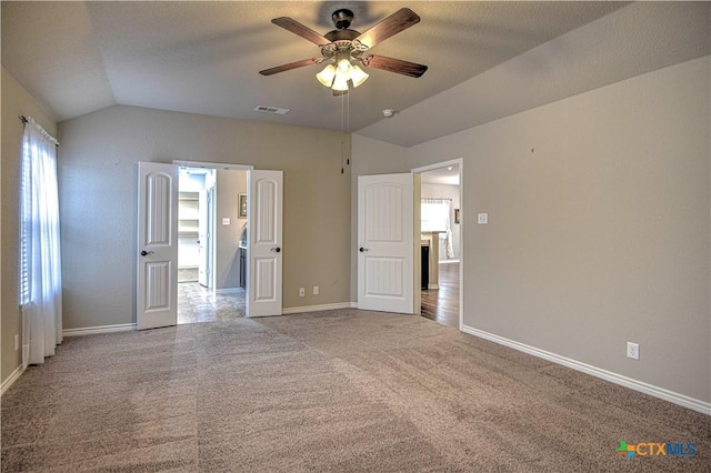 unfurnished bedroom with visible vents, a ceiling fan, carpet floors, baseboards, and vaulted ceiling