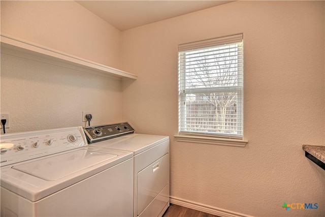 washroom featuring laundry area, washing machine and dryer, baseboards, and wood finished floors