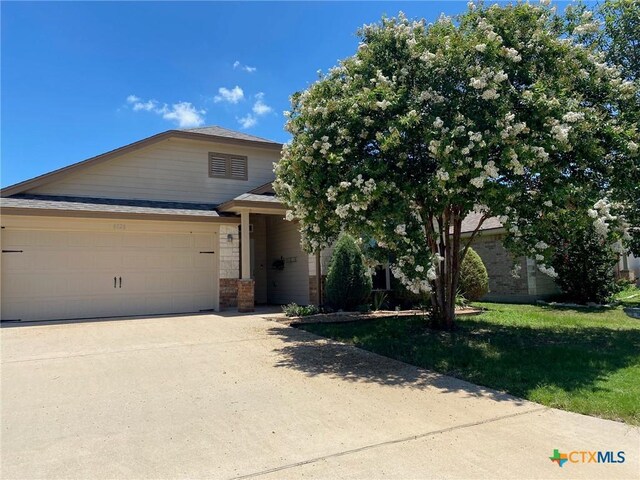 6826 Ambrose Cir, Temple, TX 76502 - view of front of house featuring driveway, a front yard, an attached garage, and stone siding