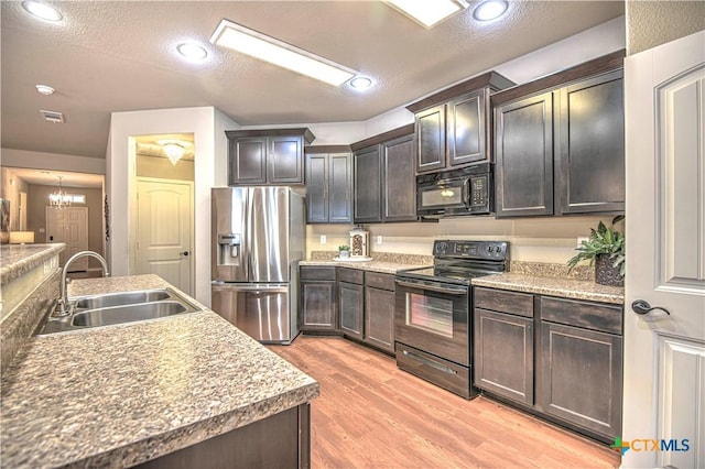 kitchen featuring visible vents, dark brown cabinetry, light wood-style flooring, black appliances, and a sink