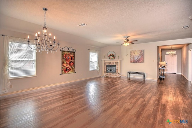 unfurnished living room with dark wood-style floors, visible vents, baseboards, a brick fireplace, and ceiling fan with notable chandelier