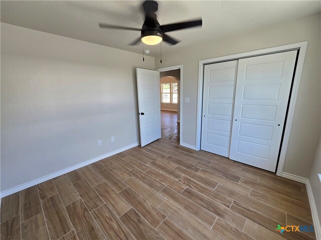 unfurnished bedroom featuring ceiling fan and a closet