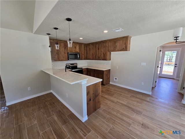 kitchen with stainless steel appliances, light wood-type flooring, decorative light fixtures, a breakfast bar area, and kitchen peninsula