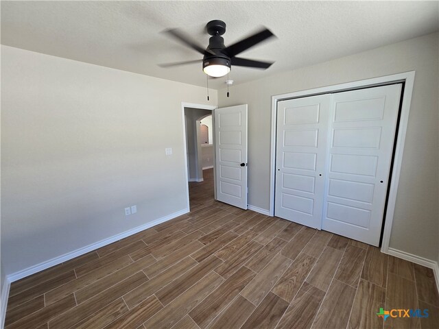 unfurnished bedroom with dark wood-type flooring, ceiling fan, a textured ceiling, and a closet