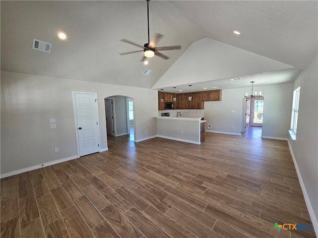 unfurnished living room featuring high vaulted ceiling, ceiling fan with notable chandelier, sink, and dark hardwood / wood-style flooring