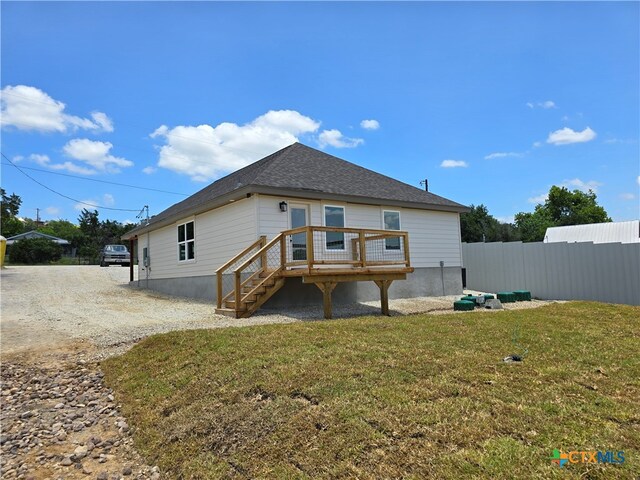 rear view of property featuring a lawn and a wooden deck