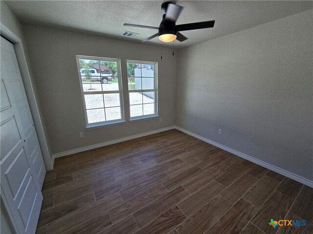 interior space featuring dark hardwood / wood-style flooring, a textured ceiling, and ceiling fan