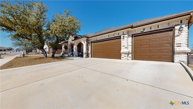 view of front of property featuring a garage, brick siding, and driveway