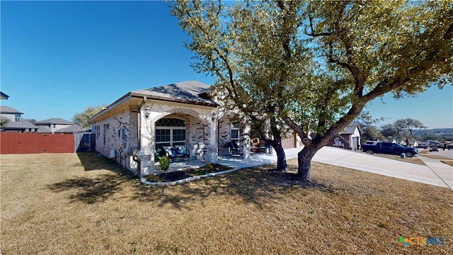 view of front of property with concrete driveway, brick siding, a front yard, and fence