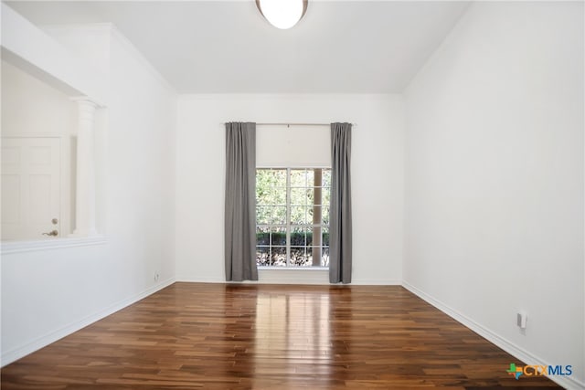 empty room featuring dark wood-type flooring and decorative columns