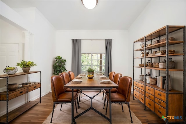 dining room with dark hardwood / wood-style flooring, decorative columns, and ornamental molding