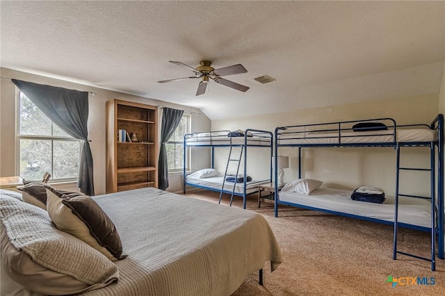 carpeted bedroom featuring vaulted ceiling, ceiling fan, and a textured ceiling