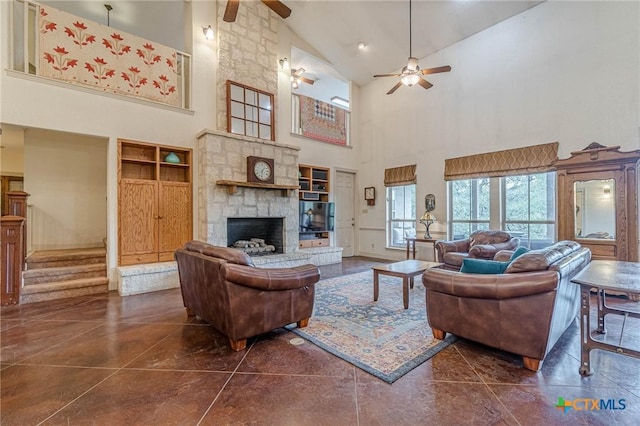 living room featuring a stone fireplace, high vaulted ceiling, dark tile patterned floors, and ceiling fan