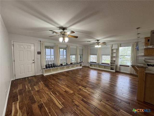 unfurnished living room featuring dark wood-type flooring, a ceiling fan, a textured ceiling, and baseboards