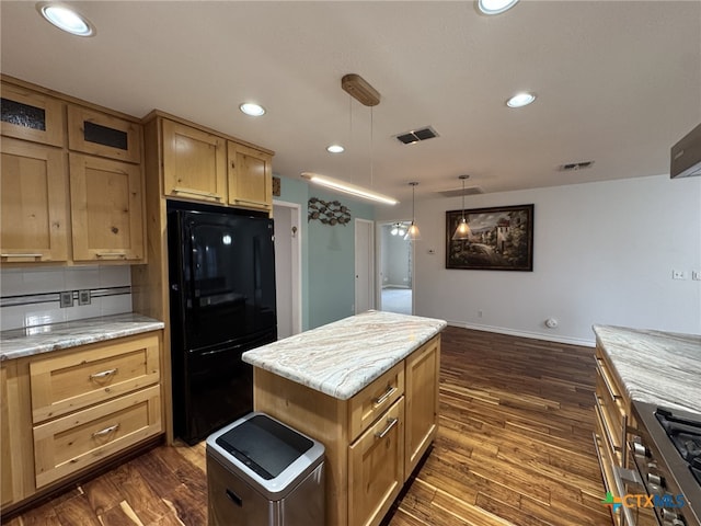 kitchen with freestanding refrigerator, baseboards, dark wood-type flooring, a kitchen island, and visible vents