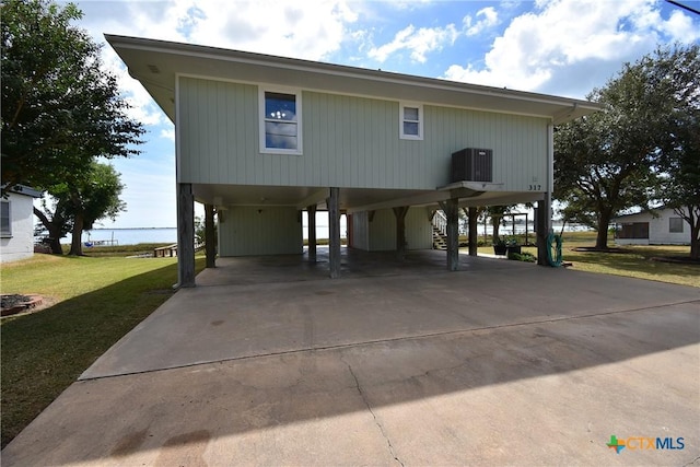 coastal inspired home with driveway, a carport, central AC, a front lawn, and stairs