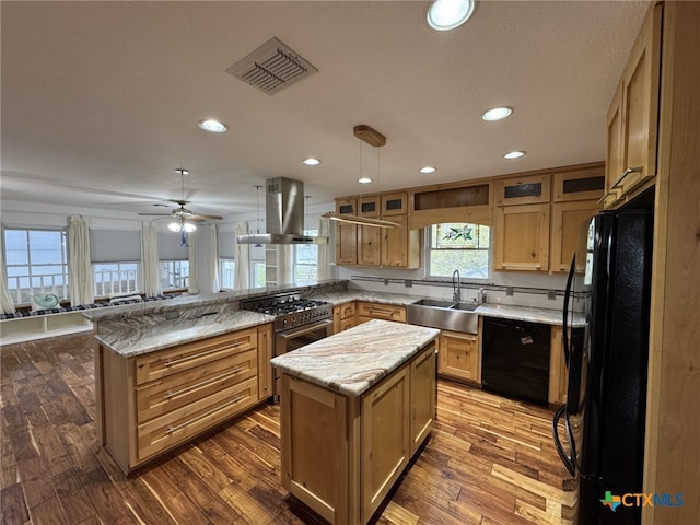kitchen with a sink, a peninsula, island range hood, visible vents, and black appliances