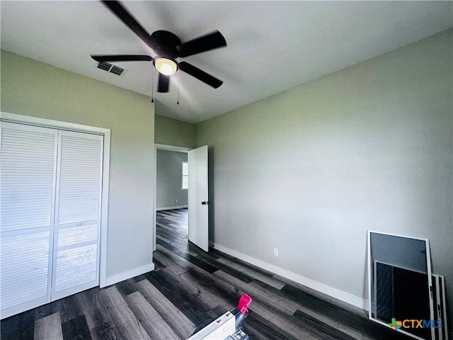 unfurnished bedroom with dark wood-type flooring, ceiling fan, and a closet