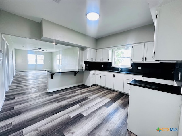 kitchen with white cabinets, decorative backsplash, wood-type flooring, and ceiling fan