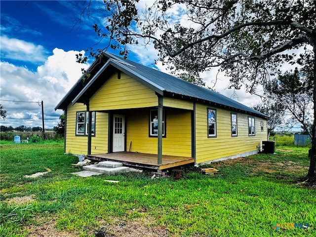 back of property with central AC unit and a lawn