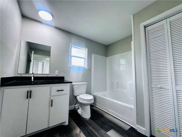 full bathroom with hardwood / wood-style floors, washtub / shower combination, vanity, and toilet