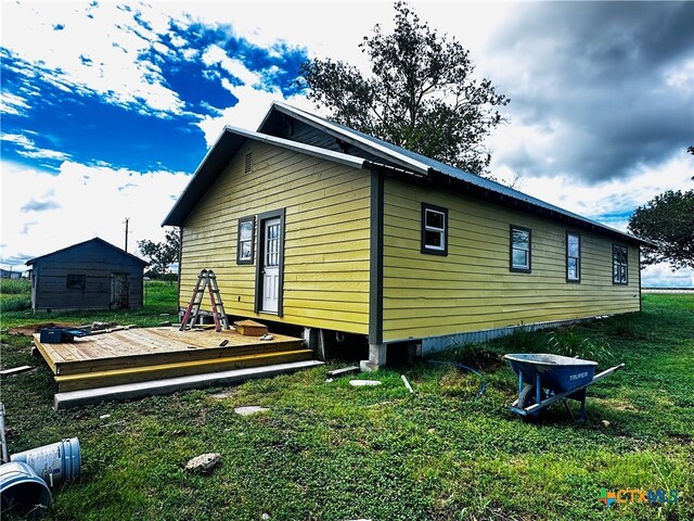 view of property exterior with a shed, a lawn, and a deck