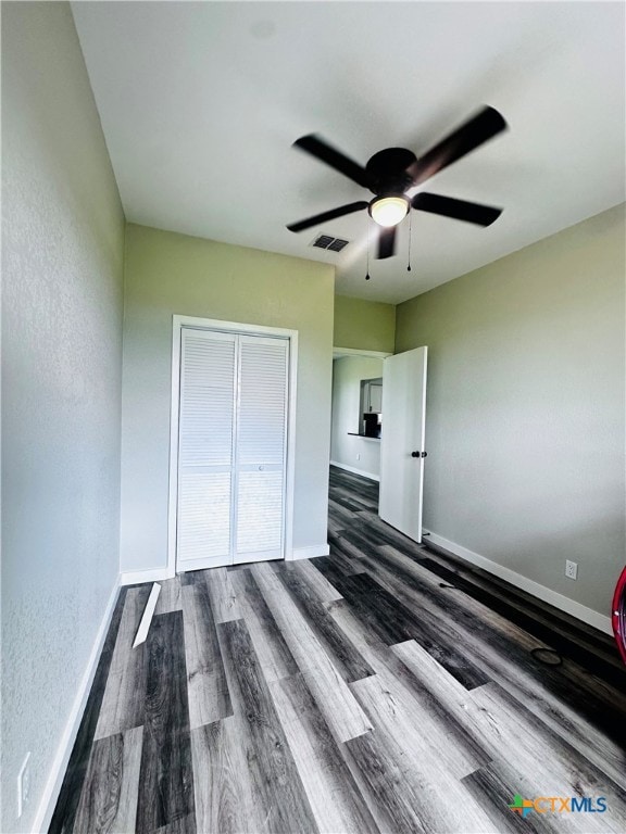 unfurnished bedroom with dark hardwood / wood-style flooring, ceiling fan, and a closet