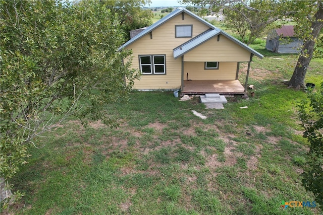 back of house featuring a lawn and a wooden deck