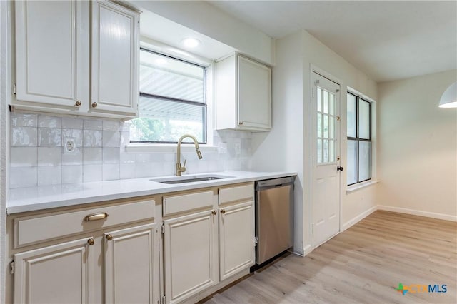 kitchen featuring stainless steel dishwasher, light hardwood / wood-style floors, sink, and decorative backsplash