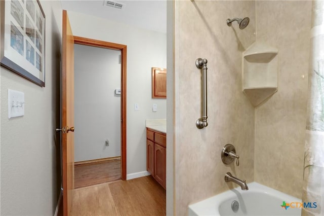 full bath featuring visible vents, tub / shower combination, baseboards, wood finished floors, and vanity