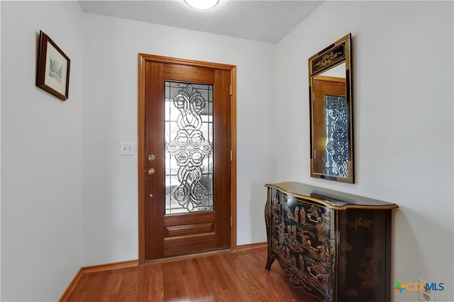 entrance foyer featuring baseboards, a textured ceiling, and wood finished floors