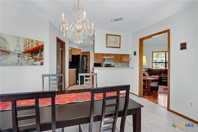 dining area featuring visible vents, marble finish floor, a textured ceiling, an inviting chandelier, and baseboards