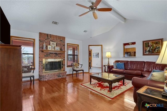 living room featuring beam ceiling, visible vents, wood-type flooring, and ceiling fan