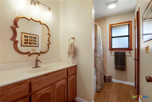 full bath with baseboards, shower / bath combo, wood finished floors, and vanity