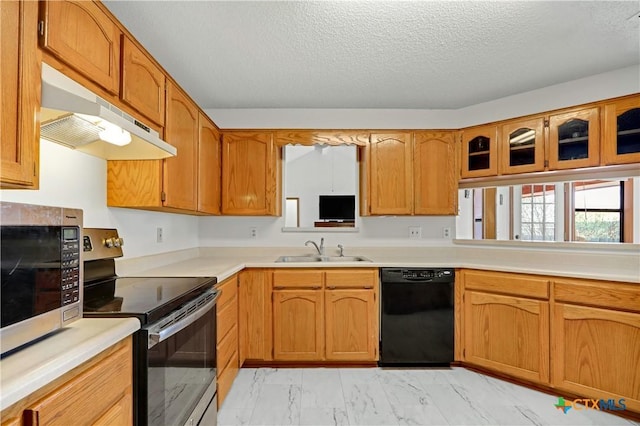 kitchen featuring marble finish floor, under cabinet range hood, a sink, stainless steel appliances, and light countertops