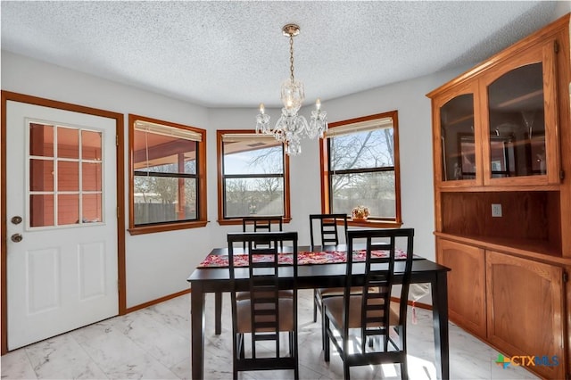 dining room with an inviting chandelier, baseboards, marble finish floor, and a textured ceiling