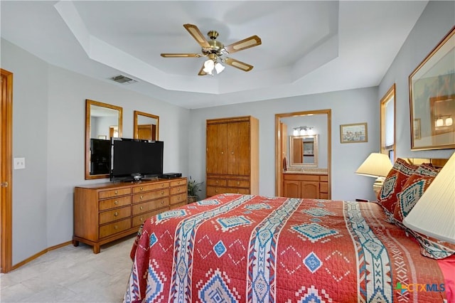 bedroom featuring visible vents, connected bathroom, baseboards, and a tray ceiling